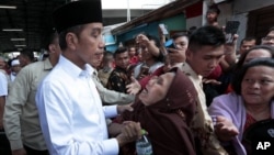 Presiden Indonesia Joko Widodo (kiri), mendengarkan seorang wanita lanjut usia saat melakukan lawatan ke Tanah Tinggi, kawasan hunian masyarakat berpenghasilan rendah, di Jakarta, Jumat, 26 Juli 2019. 