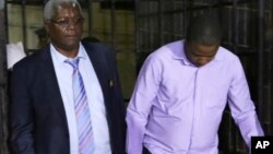  Zimbabwe's former finance minister, Ignatius Chombo, center and Kudzanai Chipanga are led to a prison truck in Harare, Zimbabwe, Nov. 25, 2017. Chombo testified that armed men in masks and uniforms abducted him from his home during the military operation