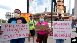 People hold signs during a rally protesting housing eviction, in Boston, June 9, 2021. 