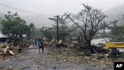 Warga setempat berjalan melewati jalanan yang porak poranda dipenuhi sampah dan serpihan pasca hantaman topan Evan di ibukota Samoa, Apia (14/12). Warga Fiji bersiap menghadapi topan Evan yang diperkirakan akan melanda wilayahnya, Minggu (16/12).