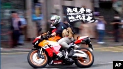 FILE - Motorcyclist Tong Ying-kit carries a flag reading "Liberate Hong Kong, Revolution of our times" during a protest in Hong Kong July 1, 2020, the anniversary of its return to China.