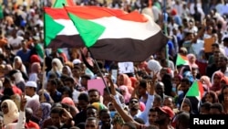 FILE - Sudanese protesters and wave flags during a rally at the Green Square in Khartoum, Sudan, July 18, 2019. 