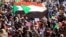 FILE - Sudanese protesters and wave flags during a rally at the Green Square in Khartoum, Sudan, July 18, 2019. 