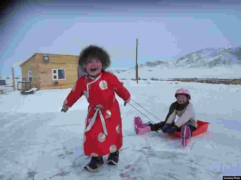 Dua gadis kecil dari keluarga penggembala di Mongolia bermain di atas es (foto telah dikirim oleh Iderjargal untuk Kontes Foto VOA).