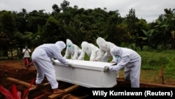Des employés municipaux portent le cercueil d'une victime du coronavirus dans une zone d'enterrement fournie par le gouvernement à Bogor, en Indonésie, le 26 janvier 2021.