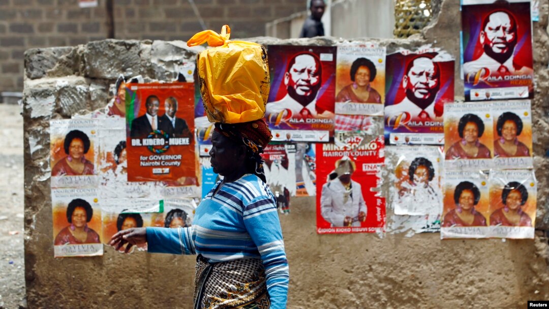 A woman walks past a wall covered with campaign posters on a street in Kenya's capital Nairobi March 3, 2013.