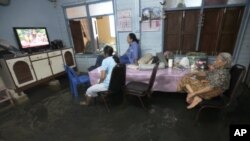 Family members watch TV lifted to avoid flooding at their home in Bangkok, Thailand, October 3, 2011.