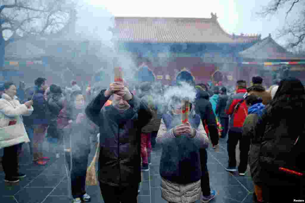 Warga membakar dupa dan berdoa untuk keberuntungan di Kuil Yonghegong Lama pada hari pertama tahun baru ayam jantan di Beijing (28/1). (Reuters/Damir Sagolj).