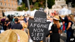 A woman holds a banner reading "Afghan sisters, you're not alone" during a demonstration in favor of Afghan women's rights, staged by women rights activists, in Rome, Sept. 25, 2021.