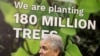 Colombia's President Ivan Duque reacts beneath a sign reading "We are planting 180 million trees" during the COP26 UN Climate Change Conference in Glasgow, Scotland on Nov. 2, 2021.