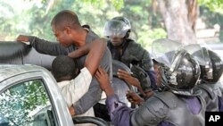 Vijana wanaoaminika ni wa upinzani wakilazimishwa na polisi kuingia ndani ya gari baada ya kukamatwa mjini Kinshasa