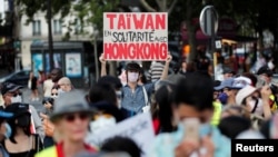 FILE - A man wearing a protective mask holds a placard reading "Taiwan in solidarity with Hong Kong," as people demonstrate in support of Hong Kong protesters opposed to China's national security law, in Paris, France, July 11, 2020.