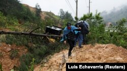 Orang-orang melintasi tanah longsor yang menutupi jalan setelah Badai Eta, di Purulha, Baja Verapaz, Guatemala, 6 November 2020. (Foto: REUTERS/Luis Echeverria)