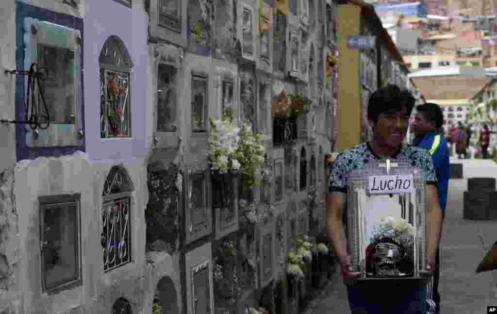 볼리비아 라파스에서 나티나스 축제가 열린 가운데 남성이 공동묘지를 들러 기도를 한 후 꽃과 안경으로 장식한 해골을 들고 이동하고 있다. 나타나스 축제는 볼리비안인들이 집안에 모셔두던 해골을 들고 참여하는 축제로, 해골이 악령을 퇴치하고 가족을 불운으로부터 보호한다고 믿는다.