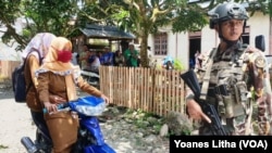 Dua perempuan melintas di depan aparat keamanan di Poso. (Foto: Yoanes Litha/ dok) 