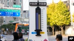 Orang-orang yang memakai masker berjalan di dekat menara elektronik yang menunjukkan tingkat vaksinasi COVID-19 di sepanjang jalan di Seoul, Korea Selatan, Senin, 1 November 2021. (Foto: AP)