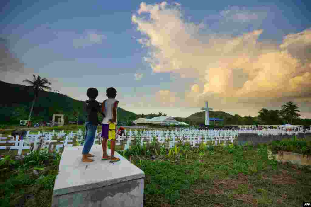 Two young residents watch as people visit the mass graveyard for victims of super Typhoon Haiyan, which hit in 2013, in Tacloban City, Leyte province, central Philippines.