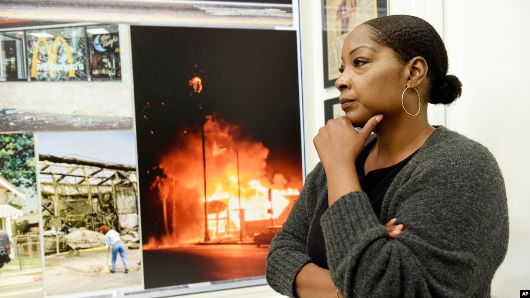 Katynja McCory, lead docent for the "Re-Imagine Justice" art exhibit, looks at L.A. Riots photos featured in the exhibit at the Community Coalition, April 18, 2017. When she thinks back to the Rodney King riots, McCory recalls that her mother told the 13-year-old to get on the floor of their home, lest she be hit by a stray bullet. 