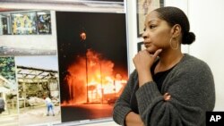 Katynja McCory, lead docent for the "Re-Imagine Justice" art exhibit, looks at L.A. Riots photos featured in the exhibit at the Community Coalition, April 18, 2017. When she thinks back to the Rodney King riots, McCory recalls that her mother told the 13-year-old to get on the floor of their home, lest she be hit by a stray bullet. 