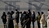 Security guards set up the barricade line as people line up to get a swab for the COVID-19 test to meet traveling requirements at a mobile coronavirus testing facility outside a commercial office buildings in Beijing, Jan. 16, 2022. 