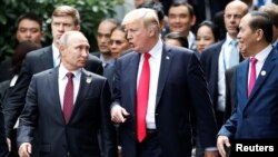 Presiden AS Donald Trump dan Presiden Rusia Vladimir Putin berbincang, sementara Presiden Vietnam Tran Dai Quang, kanan, memperhatikan dalam sesi foto bersama di KTT APEC di Danang, Vietnam, 11 November 2017.