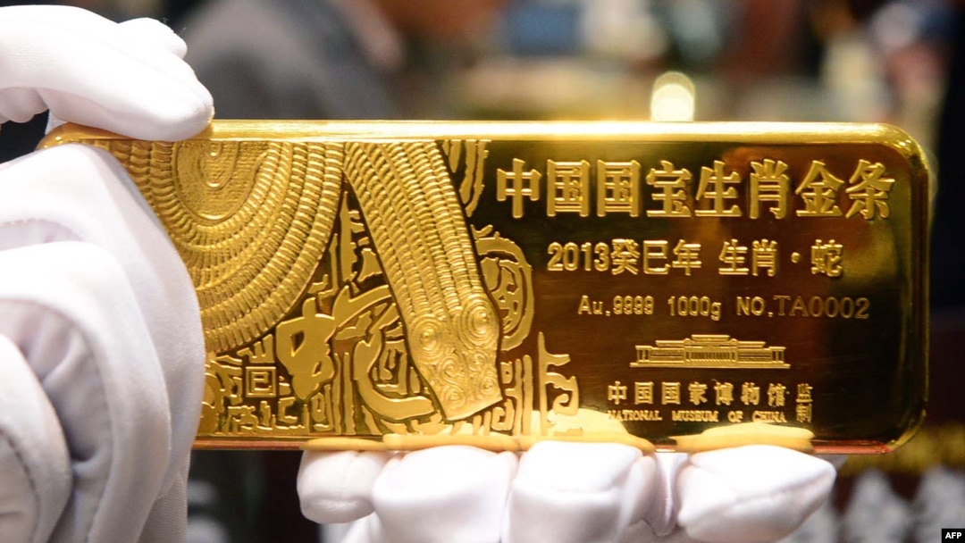 Seorang pramuniaga menunjukkan emas batangan di sebuah toko emas di Beijing, China, 7 November 2012. (Foto: AFP)