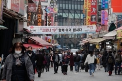 People wearing face masks walk through a market in Seoul, South Korea, March 4, 2021.