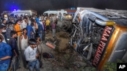 Onlookers gather near the wreckage after a bus carrying migrant workers after the lifting of coronavirus restrictions hit a delivery van on a highway near Kanpur, Uttar Pradesh state, India, June 8, 2021.