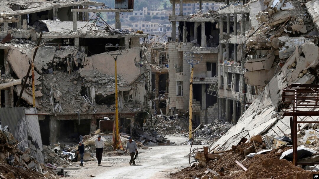 Residents walk through rubble with damaged electricity lines at the mountain resort town of Zabadani in the Damascus countryside, Syria, May 18, 2017.