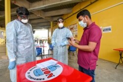 People wear protective face masks during a visit to the remittance services booth at migrant workers' dormitory during the coronavirus disease outbreak in Singapore, April 15, 2020.