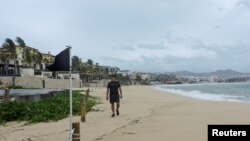 Un hombre camina por una playa con bandera negra, lo que indica que las condiciones son extremadamente peligrosas, con motivo del huracán Kay, en Cabo San Lucas, en Baja California, México, el 6 de septiembre de 2022.