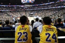 Fans in Lebron James and former player Kobe Bryant jerseys watch a game between the LA Lakers and the Brooklyn Nets, at Mercedes-Benz Arena, in Shanghai, China, Oct. 10, 2019. The NBA logos on their jerseys are covered with Chinese flags.
