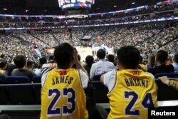 Fans in Lebron James and former player Kobe Bryant jerseys watch a game between the LA Lakers and the Brooklyn Nets, at Mercedes-Benz Arena, in Shanghai, China, Oct. 10, 2019. The NBA logos on their jerseys are covered with Chinese flags.