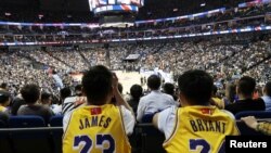Fans in Lebron James and former player Kobe Bryant jerseys watch a game between the Los Angeles Lakers against the Brooklyn Nets, at Mercedes-Benz Arena, in Shanghai, China, Oct. 10, 2019. The NBA logos on their jerseys are covered up with Chinese flags. 