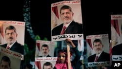 Supporters of Egypt's ousted President Mohamed Morsi posters with Arabic writing which reads "Yes for legality, No for the coup" during a protest outside Rabaah al-Adawiya mosque, Cairo, August 6, 2013.