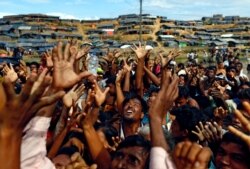 FILE - Rohingya refugees stretch their hands to receive aid distributed by local organisations at Balukhali makeshift refugee camp in Cox's Bazar, Bangladesh, Sept. 14, 2017.