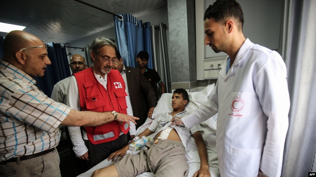 Wasu Ma'aikatan Kungiyar Red Cross da wani majinyaci a kwance a gadon asibiti.