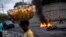 A street vendor walks past a barricade of burning tires during a demonstration against high prices and fuel shortages in Port-au-Prince, on Oct. 21, 2021. 