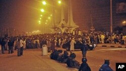 Security forces watch demonstrators protesting the elimination of a popular fuel subsidy that caused the price of petrol to double overnight gather at the Silver Jubilee roundabout in the restive central Nigerian city of Kano, January 4, 2012.