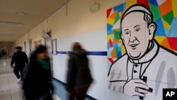 Orang-orang melewati mural Paus Fransiskus di dinding koridor Poliklinik Agostino Gemelli, tempat Paus dirawat sejak 14 Februari, di Roma, Sabtu, 1 Maret 2025. (Foto: AP)