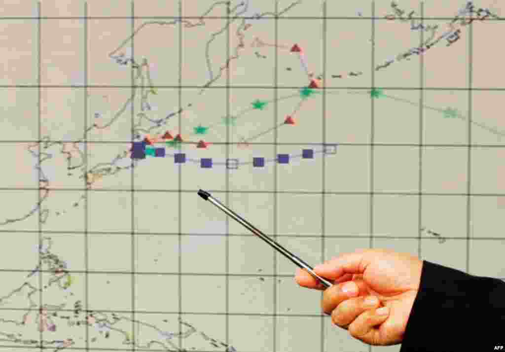 An officer at the Hong Kong Observatory shows a forecast trajectory of radiation releases from Japan during a news conference in Hong Kong Wednesday. Indicators in red triangles, blue squares and green stars project wind directions of different altitudes.