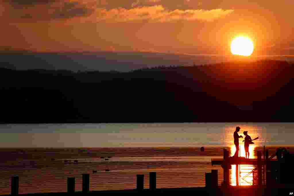 یک زوج در هنگام غروب آفتاب برای شنا در دریاچه‌ای در آلمان آماده می‌شوند