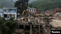 2014年8月5日,鏟土機在雲南昭通魯甸縣的地震災區現場清除廢墟，尋找遇難者遺體。 