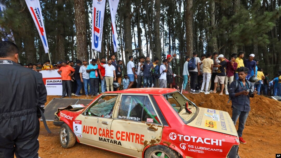 Sejumlah warga berkumpul di dekat mobil yang menabrak penonton dalam kompetisi balapan Fox Hill Supercross di Diyatalawa, Sri Lanka, pada 21 April 2024. (Foto: AP/STR)