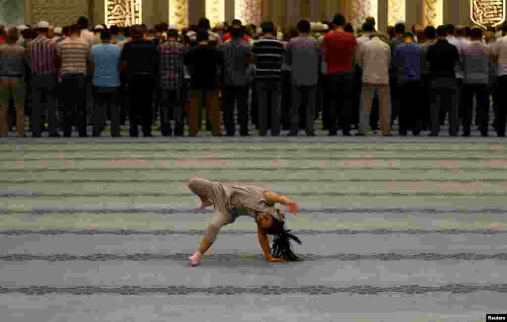 A girl plays as worshippers attend night prayers at Ahmet Hamdi Akseki Mosque in Ankara, Turkey July 14, 2015.