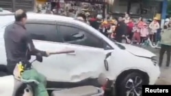 A man breaks a car's window following a vehicle collision outside a primary school in Changde, Hunan province, China in this screengrab obtained from social media video released November 19, 2024. Local authorities have not released details. Social Media/via REUTERS