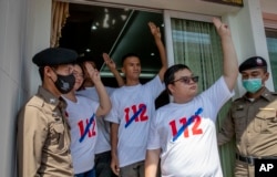 Pro-democracy movement protest leaders from right, Parit Chiwarak, Panupong Jadnok, Shinawat Chankrajang and Panusaya Sithijirawattanakul flash three-finger salute as they walk to report in a police station in Northaburi, Thailand, Tuesday, Dec. 8, 2020.