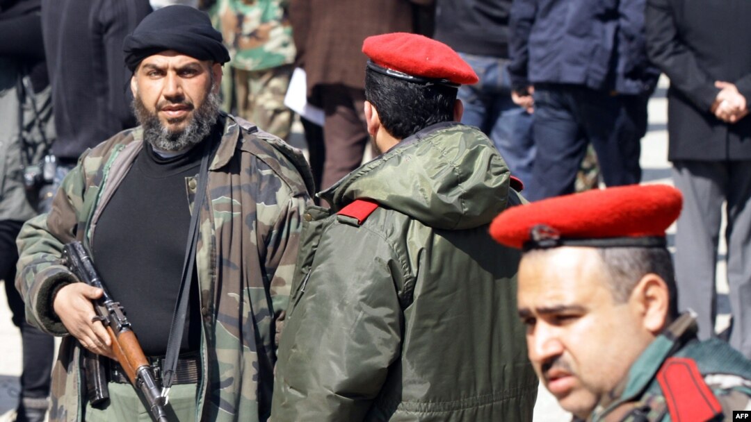 چەکدارێکی هێزەکانی بەرگری نیشتمانی سوریا کە یەکەیەکی چەکداری خۆبەخشن بۆ یارمەتیدانی بەشار ئەسەد و لەژێر فەرماندەیی سوپای سوریادا کاردەکەن.