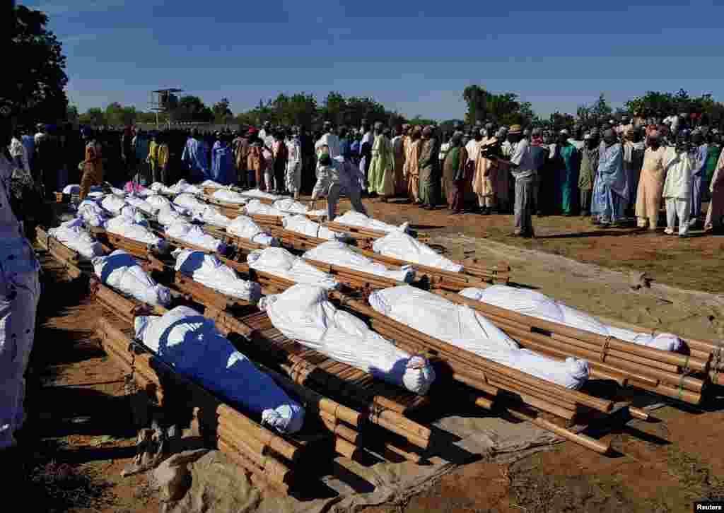 Men gather near dead bodies of people who were killed by a militant attack, during a mass burial at Zabarmari, in the Jere local government area of Borno State, in northeast Nigeria.