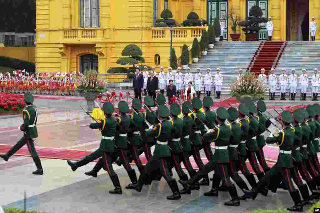 Japanese Prime Minister Shinzo Abe, left, and his Vietnamese counterpart Nguyen Xuan Phuc, second left, accompanied by their wives, Akie Abe, second right, and Tran Nguyet Thu, right, review an honor guard at the Presidential Palace in Hanoi, Vietnam.